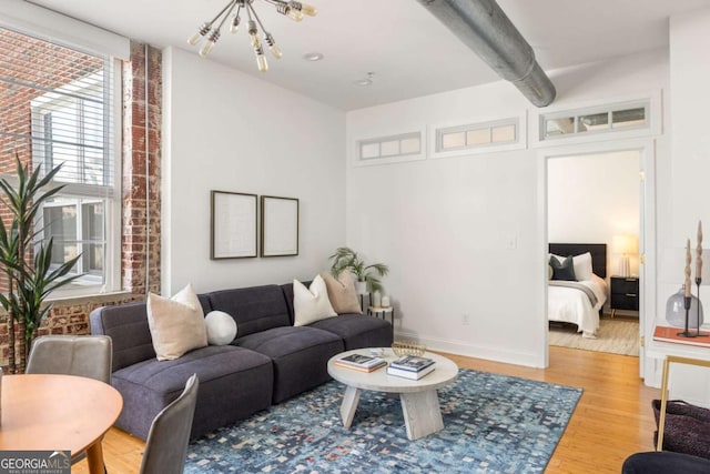 living area featuring baseboards, wood finished floors, and a notable chandelier