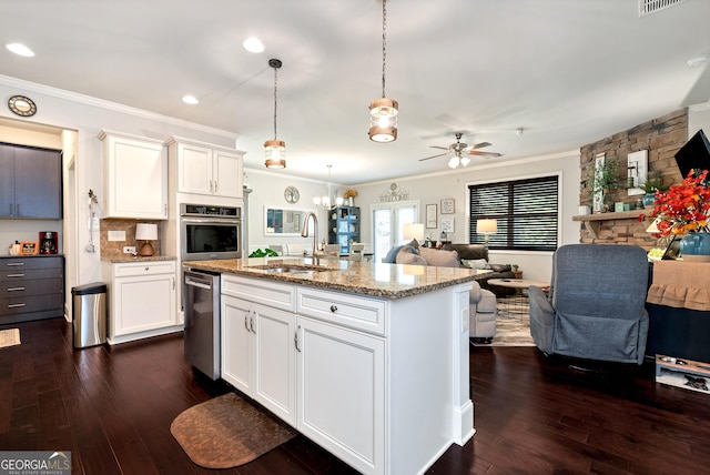 kitchen with stainless steel appliances, open floor plan, ornamental molding, and a sink