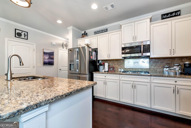 kitchen with light stone countertops, stainless steel appliances, ornamental molding, a sink, and visible vents