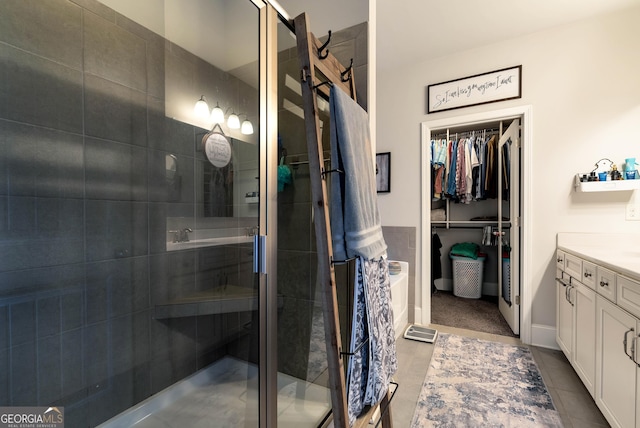 bathroom featuring vanity, a shower stall, tile patterned flooring, and a walk in closet