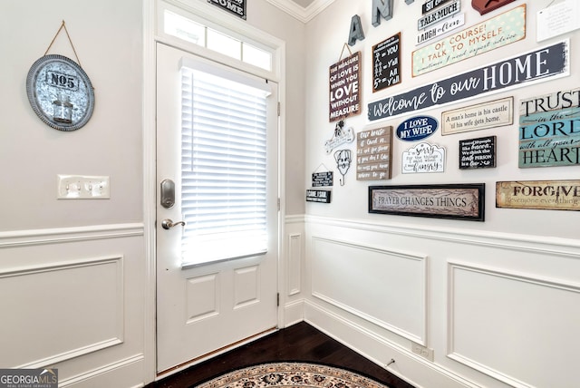 doorway featuring a decorative wall, a wainscoted wall, ornamental molding, and dark wood-style floors