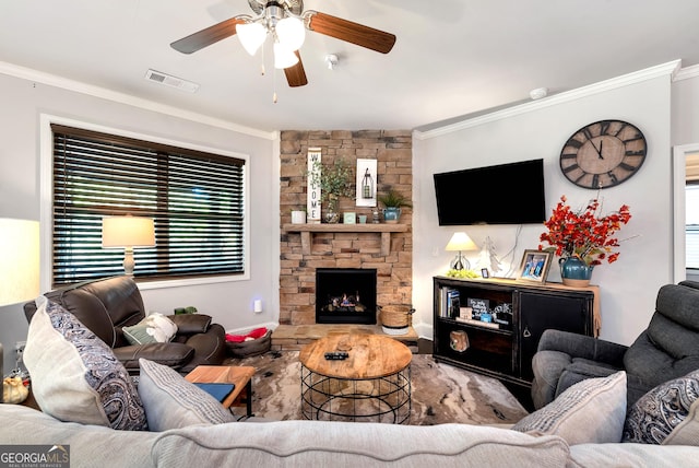 living area featuring visible vents, a ceiling fan, a fireplace, and crown molding