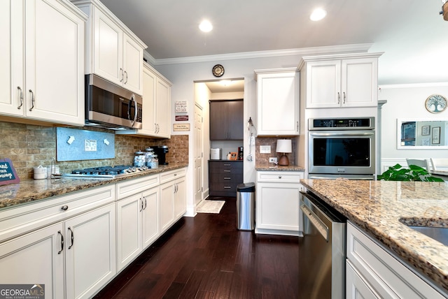 kitchen with white cabinets, appliances with stainless steel finishes, dark wood-style flooring, light stone countertops, and ornamental molding