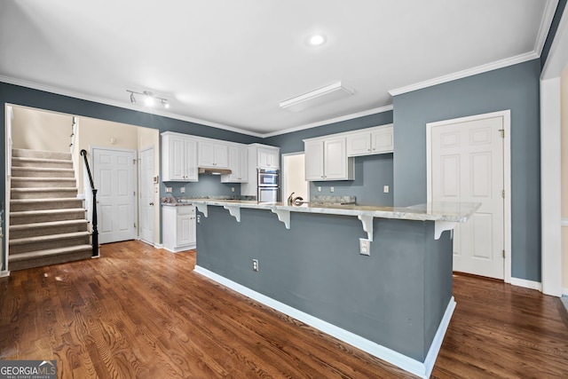 kitchen with a breakfast bar, white cabinets, and ornamental molding