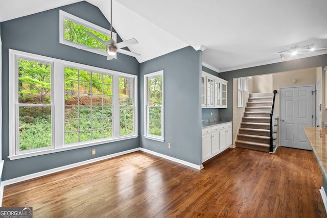 unfurnished living room featuring stairway, a ceiling fan, dark wood-style floors, and plenty of natural light