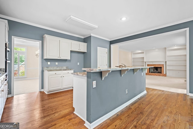 kitchen with white cabinets, open floor plan, a kitchen breakfast bar, and crown molding