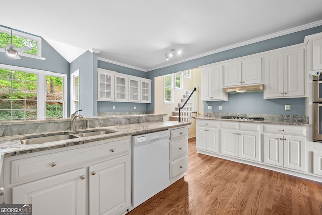 kitchen with stainless steel gas stovetop, under cabinet range hood, a sink, white dishwasher, and white cabinetry