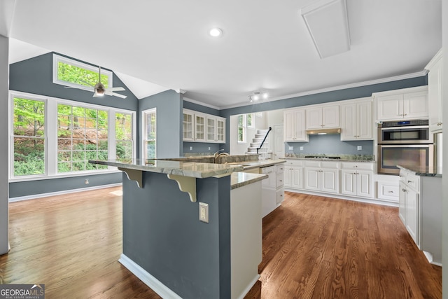 kitchen featuring gas cooktop, white cabinets, a large island with sink, a sink, and stainless steel double oven