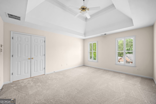 unfurnished bedroom with baseboards, carpet flooring, visible vents, and a raised ceiling