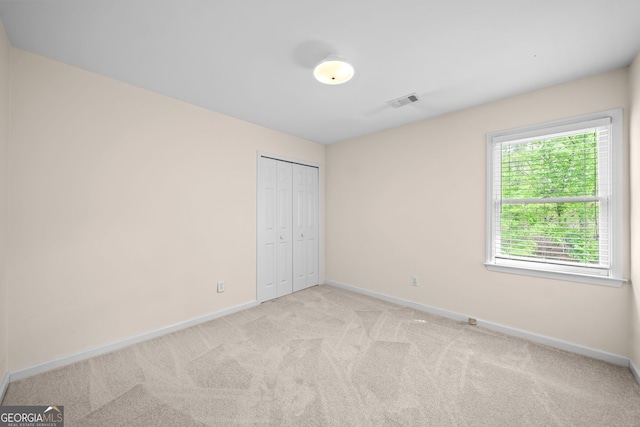 unfurnished bedroom featuring baseboards, a closet, and light colored carpet