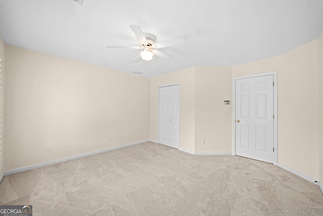 spare room with light carpet, a ceiling fan, and baseboards