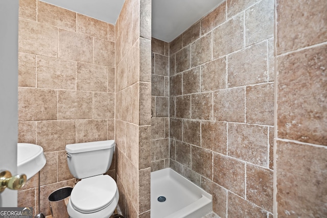 bathroom with a shower stall, toilet, and tile walls