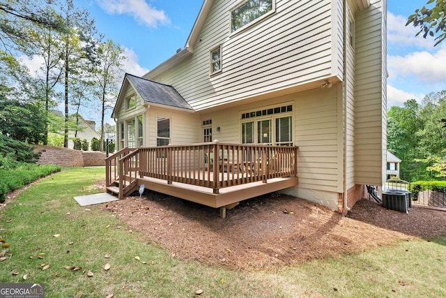 back of property with a wooden deck, a lawn, fence, and roof with shingles