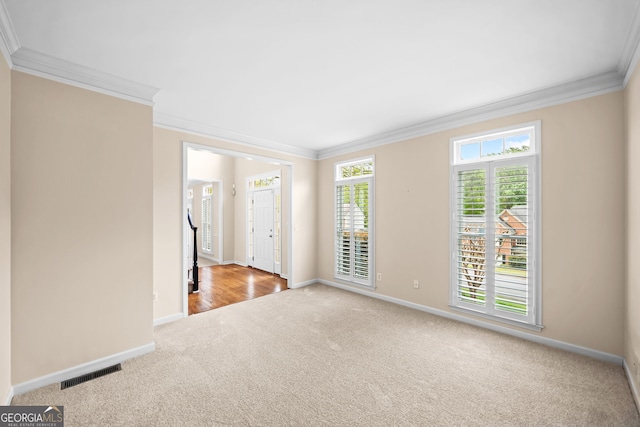 carpeted spare room featuring baseboards, visible vents, and ornamental molding