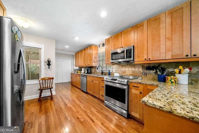 1505 Robinhood Trl, Gainesville, GA 30501 - kitchen featuring appliances with stainless steel finishes, light wood finished floors, tasteful backsplash, brown cabinets, and recessed lighting