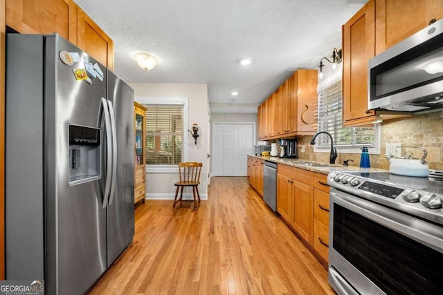1505 Robinhood Trl, Gainesville, GA 30501 - kitchen with appliances with stainless steel finishes, light wood finished floors, brown cabinets, tasteful backsplash, and healthy amount of natural light