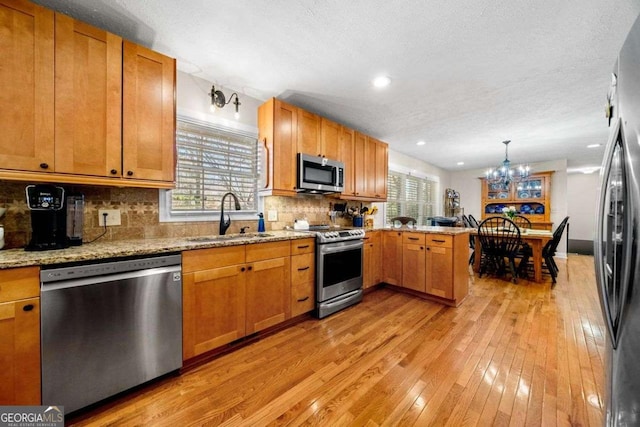 1505 Robinhood Trl, Gainesville, GA 30501 - kitchen with stainless steel appliances, a peninsula, light wood-style floors, tasteful backsplash, and a chandelier