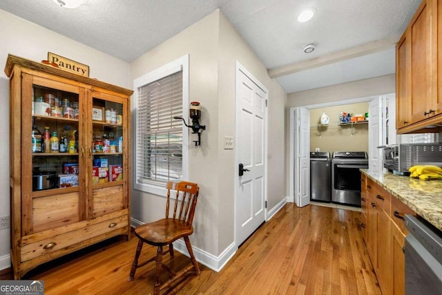 1505 Robinhood Trl, Gainesville, GA 30501 - kitchen with light wood finished floors, dishwashing machine, washer and dryer, brown cabinetry, and light stone countertops