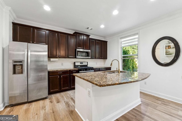 kitchen featuring ornamental molding, stainless steel appliances, a sink, stone counters, and light wood-type flooring