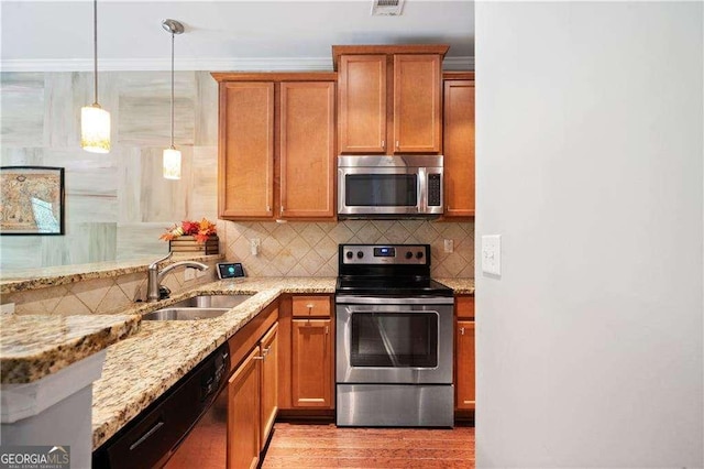 kitchen with decorative backsplash, a sink, light stone counters, appliances with stainless steel finishes, and brown cabinetry