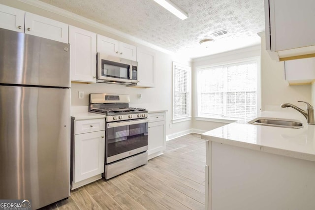 3543 Benthollow Way, Duluth, GA 30096 - kitchen with a sink, light wood finished floors, a textured ceiling, stainless steel appliances, and white cabinets