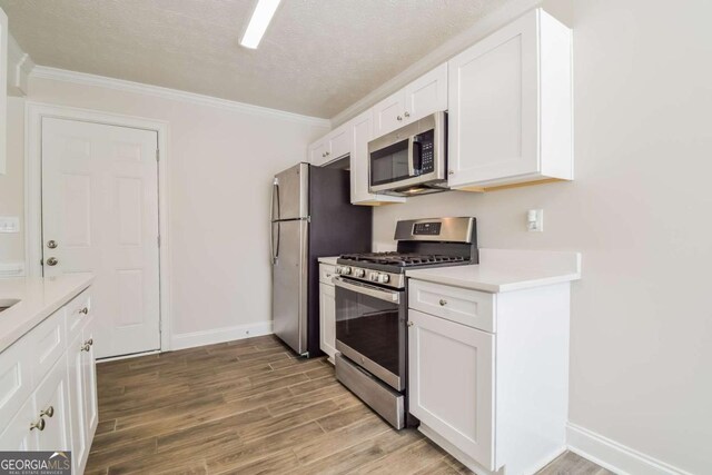 3543 Benthollow Way, Duluth, GA 30096 - kitchen featuring white cabinets, light wood-style flooring, light countertops, crown molding, and appliances with stainless steel finishes