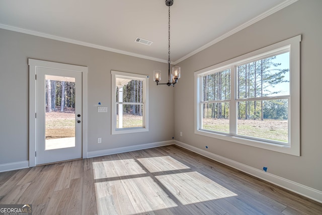 unfurnished dining area featuring healthy amount of natural light, ornamental molding, a chandelier, baseboards, and wood finished floors
