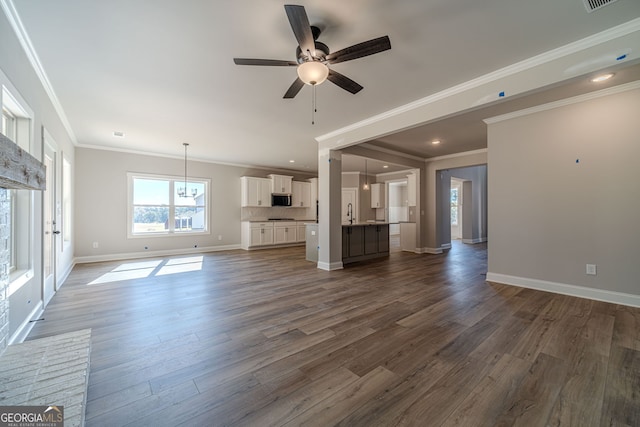 unfurnished living room featuring a ceiling fan, dark wood-type flooring, baseboards, ornamental molding, and a sink