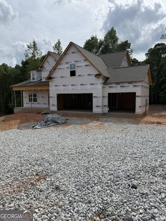 property in mid-construction with roof with shingles, driveway, and an attached garage