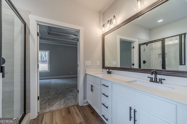 full bath featuring a stall shower, wood finished floors, double vanity, and baseboards