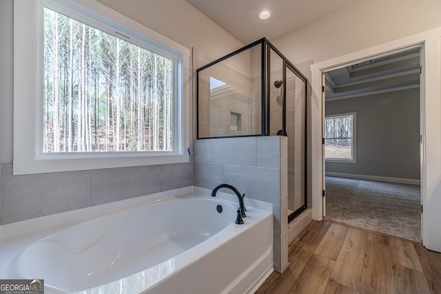 bathroom with a shower stall, a bath, recessed lighting, baseboards, and wood finished floors