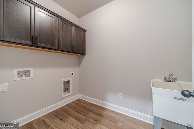 washroom with cabinet space, hookup for an electric dryer, hookup for a washing machine, light wood-type flooring, and baseboards