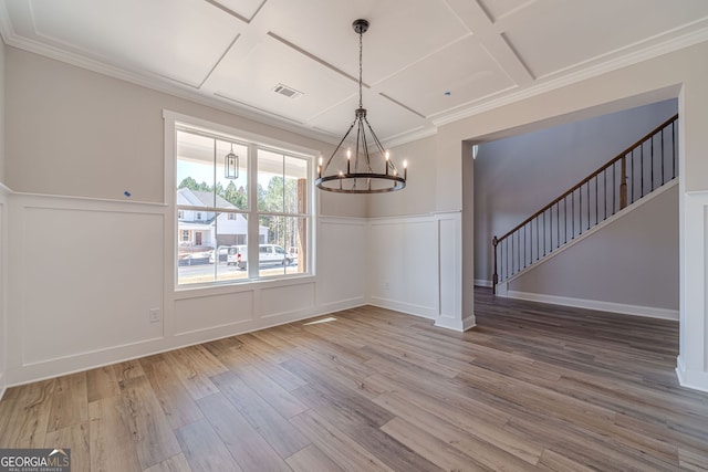 unfurnished dining area with coffered ceiling, a chandelier, wood finished floors, stairway, and a decorative wall