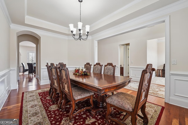 2220 Stirling Bridge Rd, Cumming, GA 30041 - dining space featuring a decorative wall, a raised ceiling, arched walkways, dark wood finished floors, and a notable chandelier