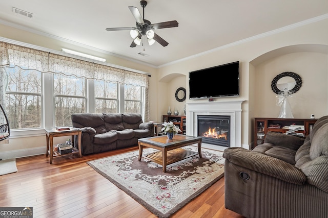 2220 Stirling Bridge Rd, Cumming, GA 30041 - living area with crown molding, a ceiling fan, light wood-style flooring, visible vents, and arched walkways