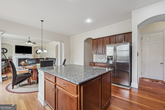 2220 Stirling Bridge Rd, Cumming, GA 30041 - kitchen featuring a kitchen island, stainless steel fridge, arched walkways, ceiling fan, and dark stone counters