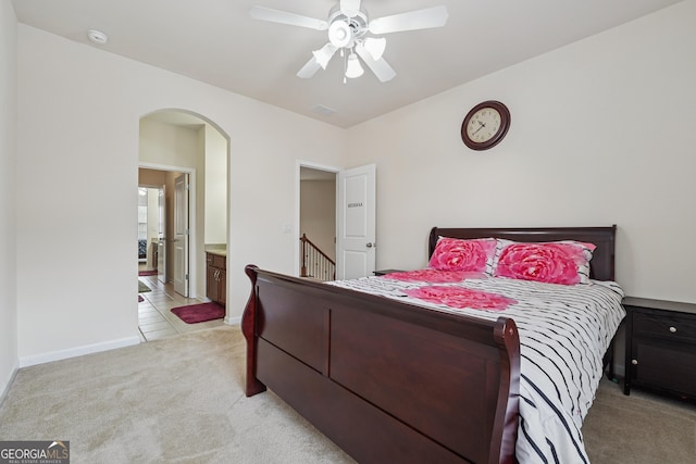 2220 Stirling Bridge Rd, Cumming, GA 30041 - bedroom with connected bathroom, a ceiling fan, light carpet, baseboards, and arched walkways