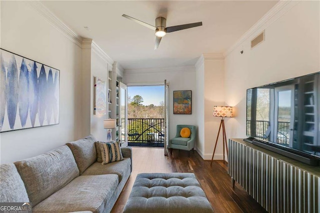 living room featuring visible vents, crown molding, baseboards, wood finished floors, and a ceiling fan