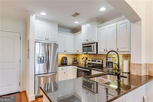 kitchen with stainless steel appliances, a sink, visible vents, white cabinets, and a peninsula
