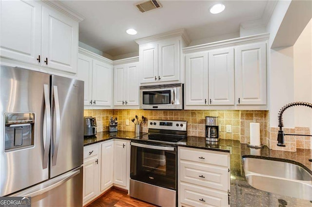 kitchen with a sink, white cabinetry, appliances with stainless steel finishes, visible vents, and decorative backsplash