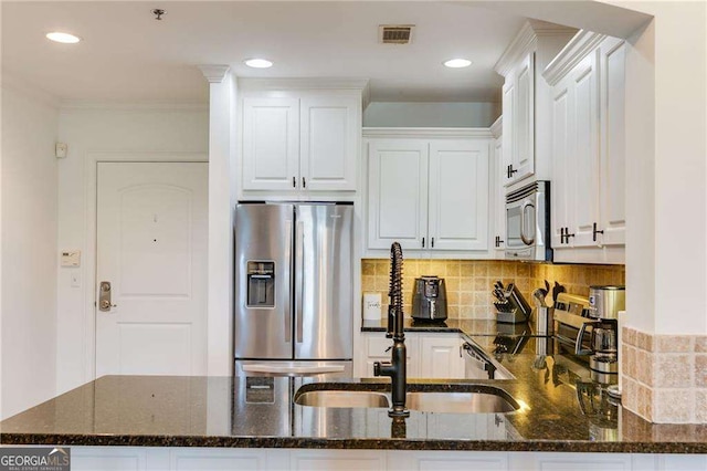 kitchen featuring tasteful backsplash, stainless steel appliances, visible vents, white cabinets, and dark stone counters