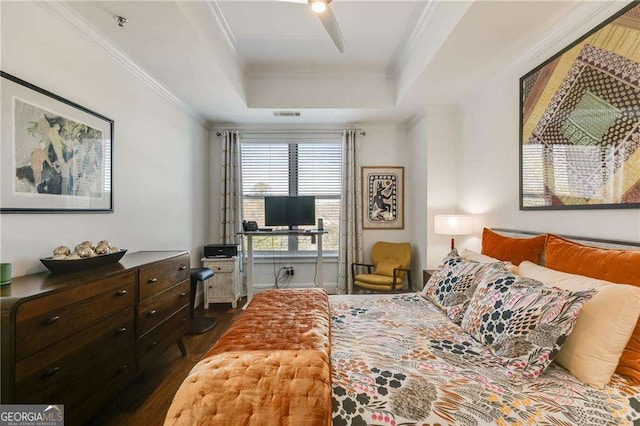 bedroom with dark wood-style flooring, a tray ceiling, and crown molding