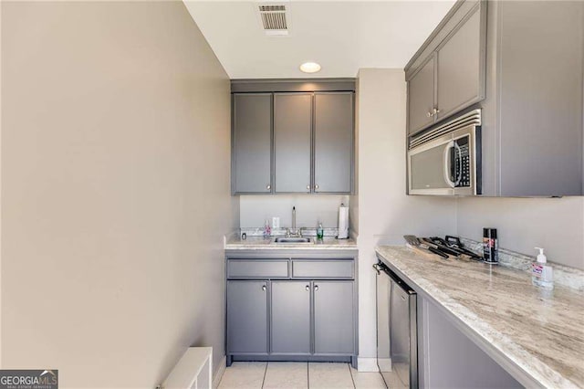 kitchen with light tile patterned flooring, visible vents, stainless steel microwave, and gray cabinets