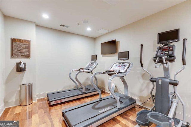 exercise area featuring baseboards, visible vents, wood finished floors, and recessed lighting