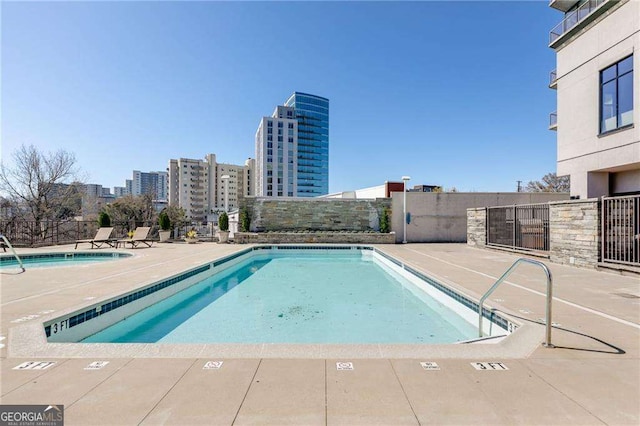 community pool featuring a view of city, fence, and a patio