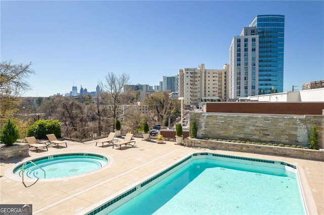 community pool featuring a hot tub, a view of city, and a patio