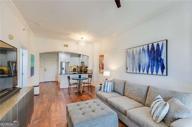 living area featuring visible vents, crown molding, arched walkways, and dark wood-type flooring