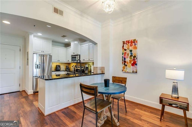 2277 Peachtree Rd NE Unit 608, Atlanta, GA 30309 - kitchen with stainless steel appliances, ornamental molding, dark countertops, a peninsula, and decorative backsplash