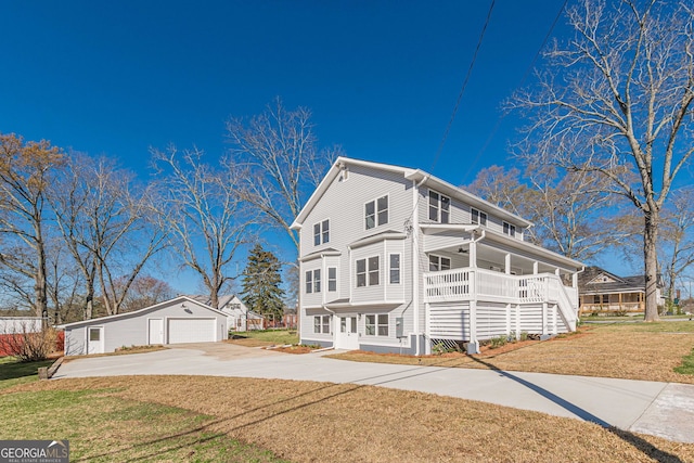 view of front of house featuring a garage, a front lawn, driveway, covered porch, and an outdoor structure