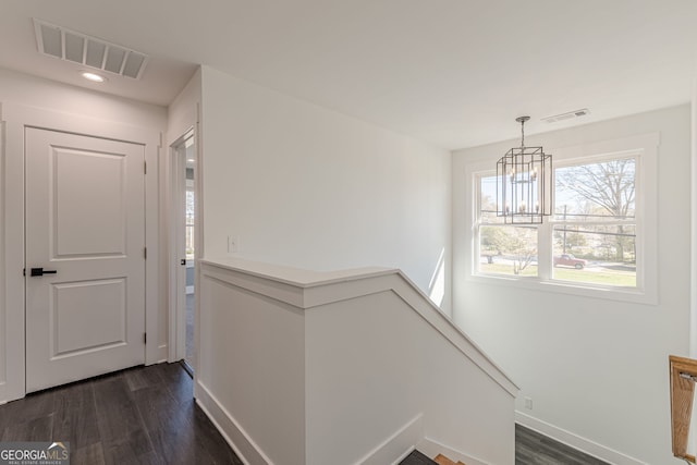 foyer with an inviting chandelier, dark wood-style flooring, and visible vents